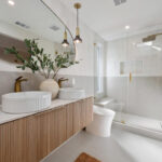 Modern bathroom with wood fluted floating vanity, double vessel sinks, and glass shower enclosure.